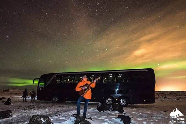 Man Playing Guitar by the Northern Lights