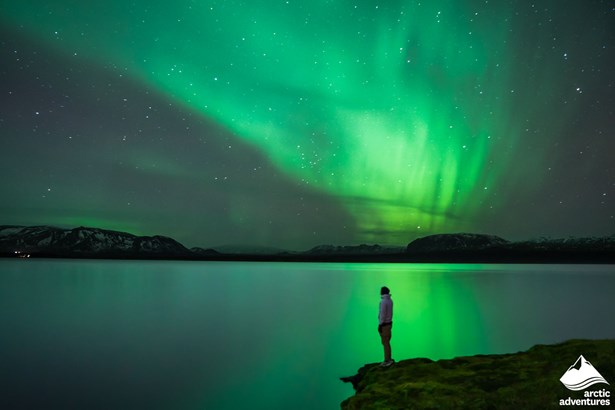 Man Watching Northern Lights by Lake in Iceland
