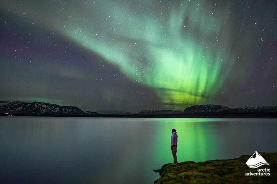 Man Watching Northern Lights in Iceland by Lake