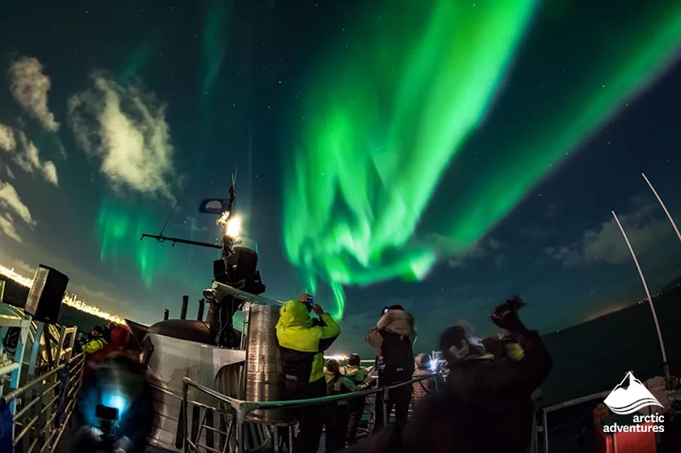 People Watching Aurora from Boat in Iceland