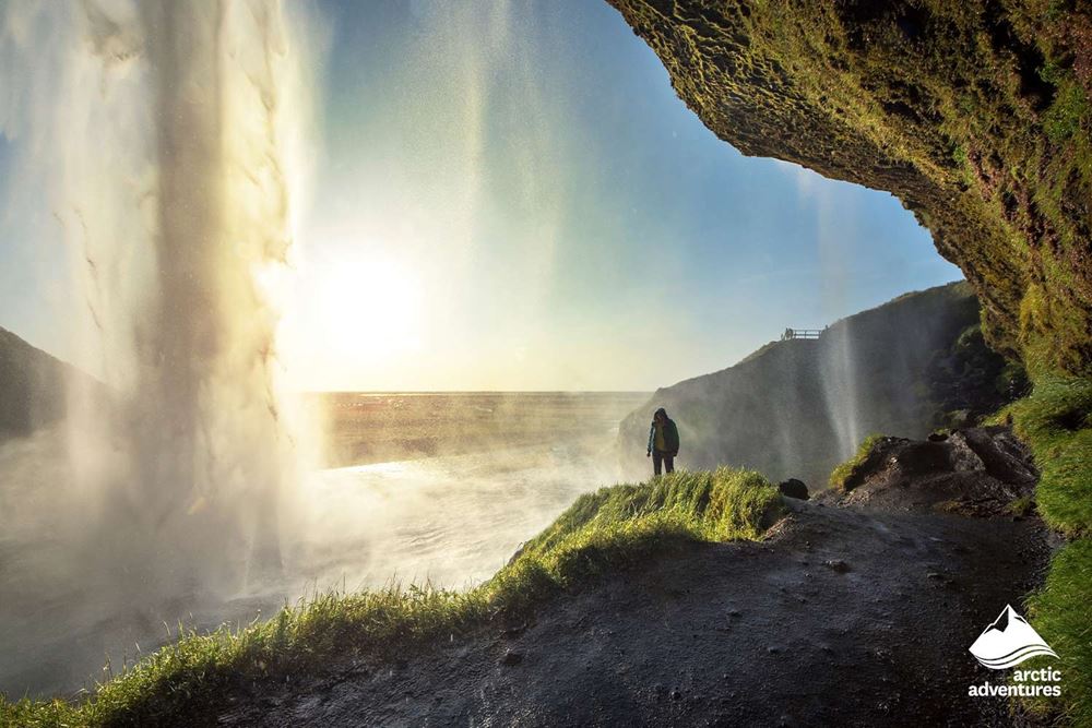 Man Standing by Waterfall