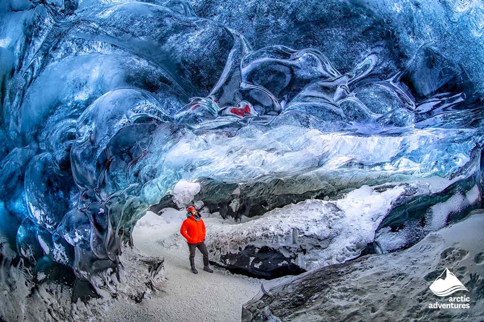 Man with Red Jacket in Clear Blue Ice Cave