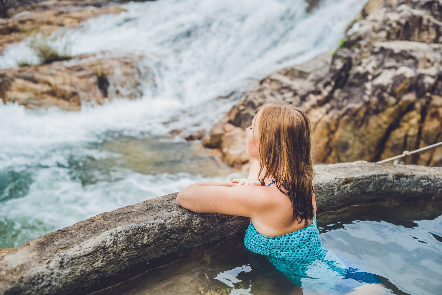 Woman Enjoying Hot Tub Overlooking Waterfall In Iceland