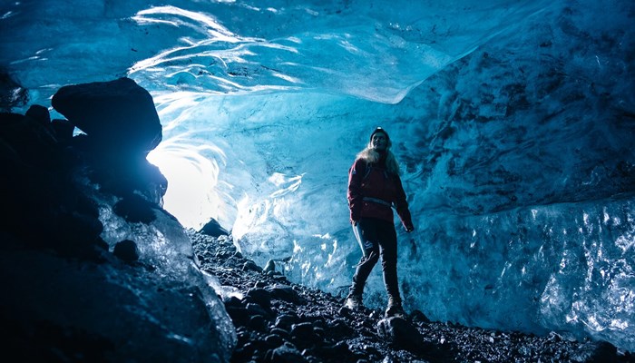 Interior of a dark blue ice cave with woman inside