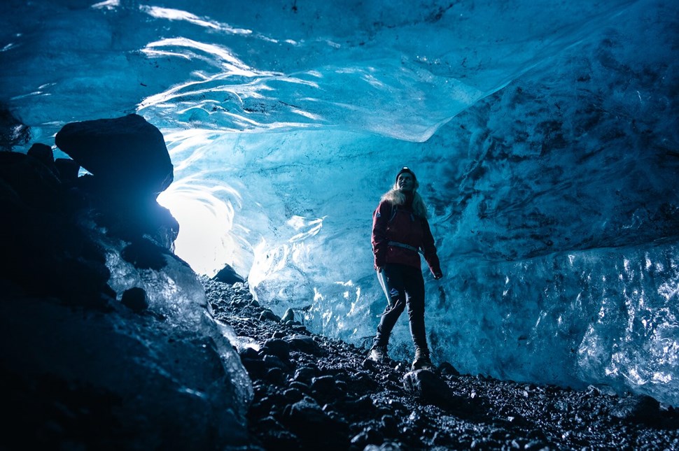 Interior of a dark blue ice cave with woman inside