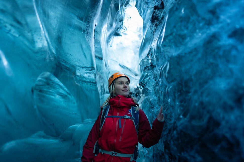 Woman looking up at the bright blue ice formations of Crystal Ice Cave in wonder