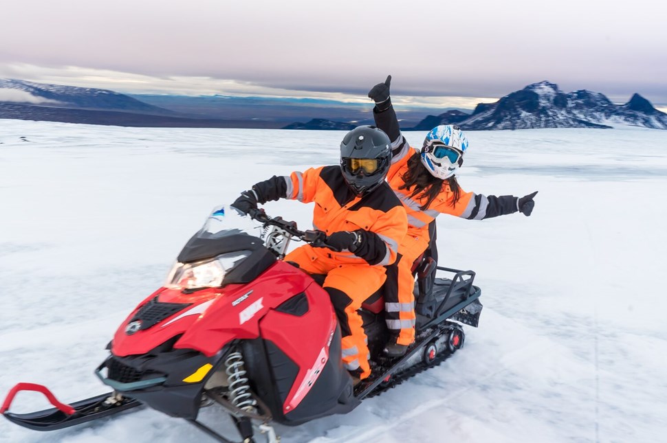 A couple snowmobiling on a glacier
