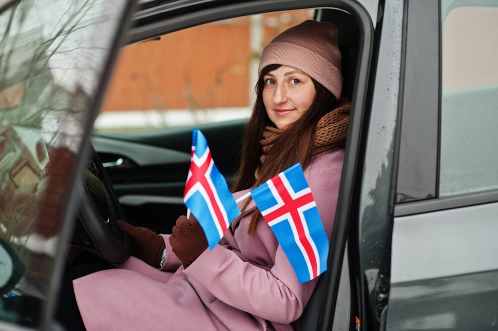 Young woman with Iceland flag sitting in a car