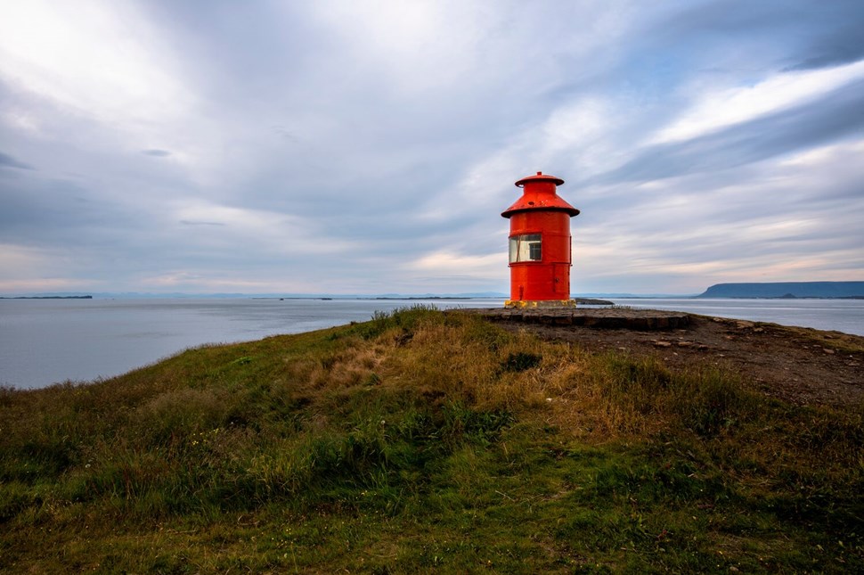  Red lighthouse overlooking calm waters under a cloudy sky autumn view