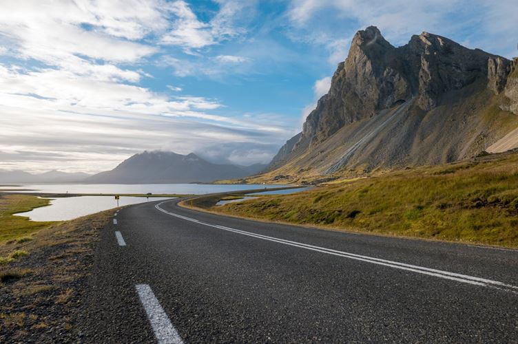 Scenic view of an empty road leading towards mountains Scenic view of an empty winding road leading towards a majestic mountain range