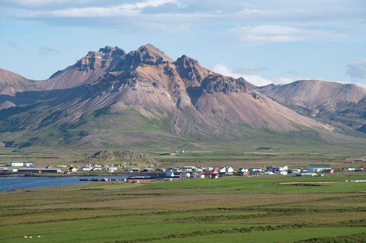 Mountains overlooking Icelandic village  Mountains overlooking a coastal village with colorful buildings amidst green fields