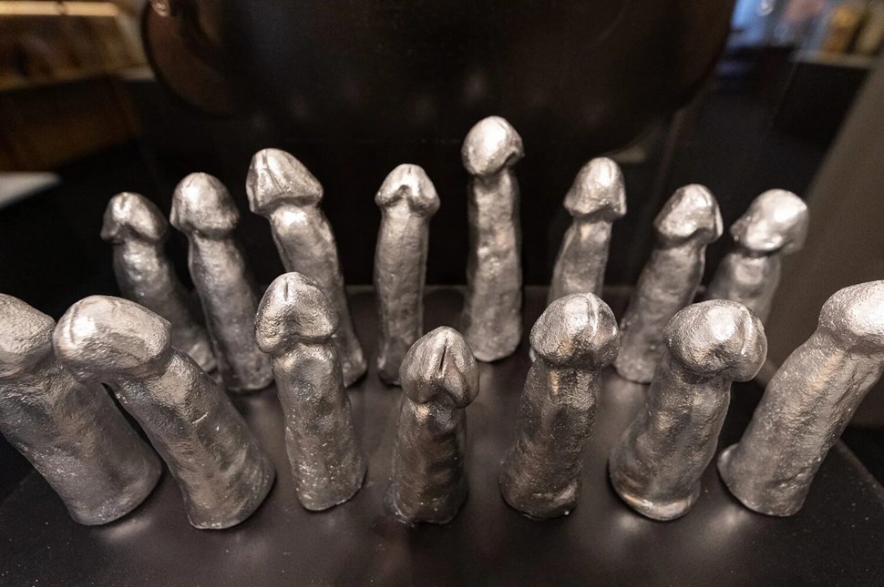 Metallic phallic sculptures on display.