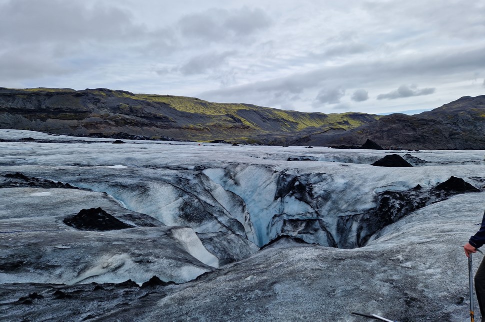 View of ice-covered ash and mountains in the distance on a glacier in Iceland