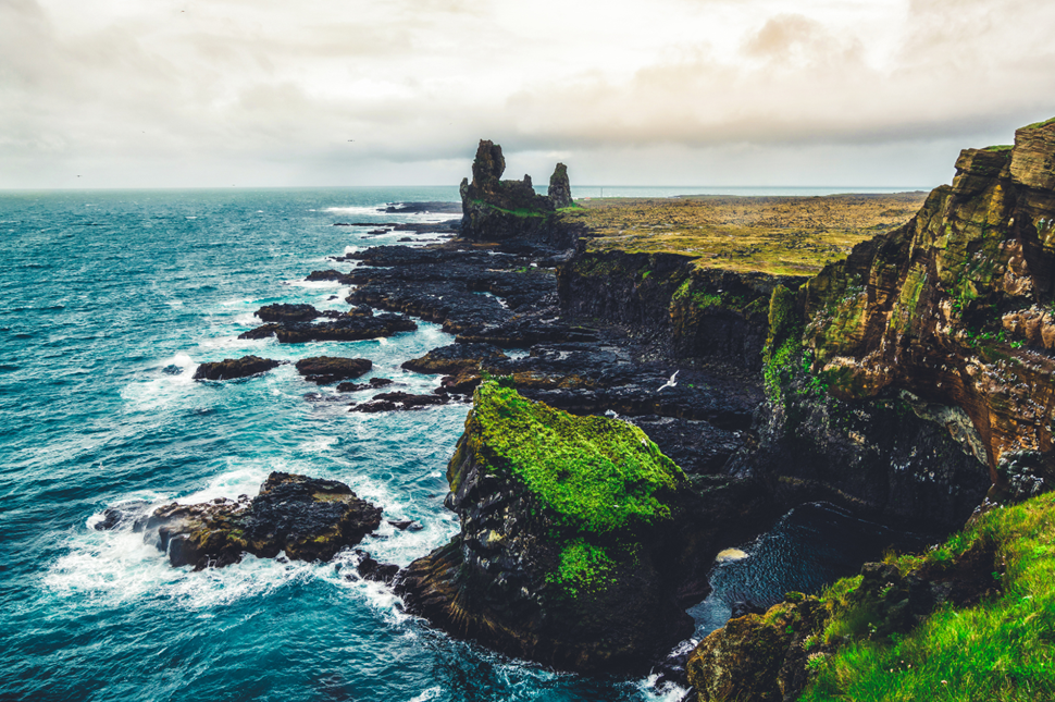 Blue waves crashing against the rocky cliffs of Lóndrangar in Snæfellsnes National Park, West Iceland