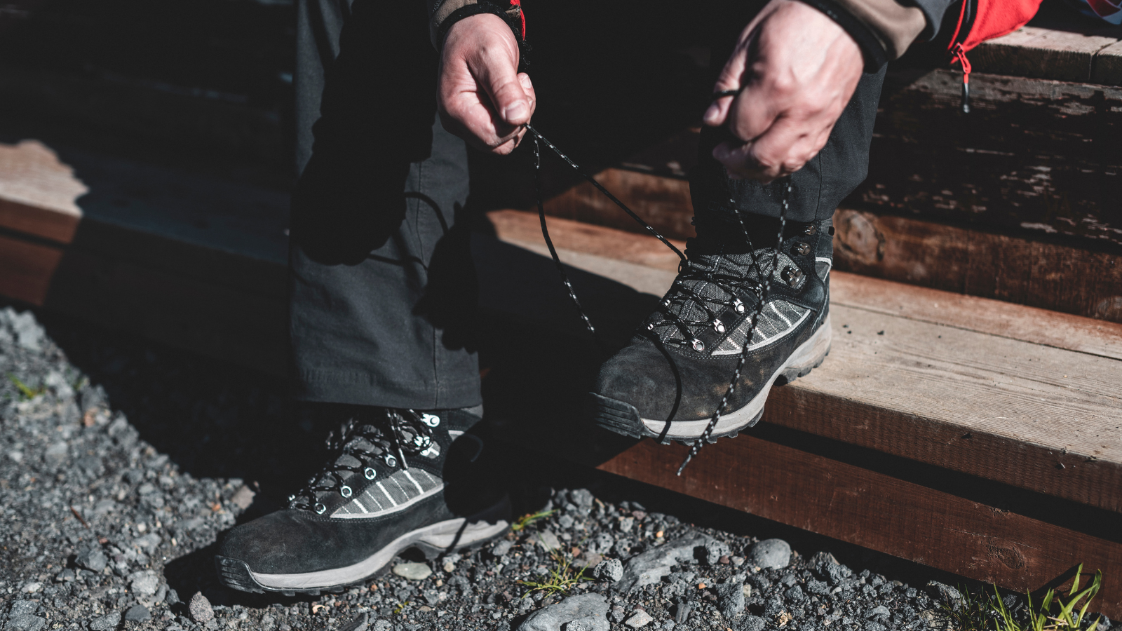 Man tying his laces on his hiking boots on a wooden step