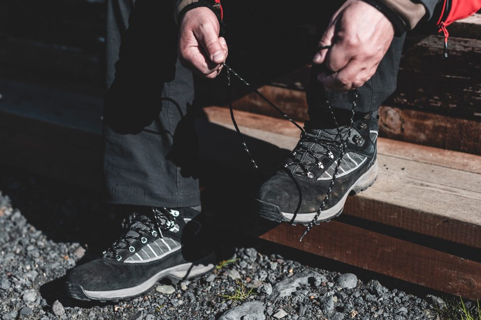 Man tying his laces on his hiking boots on a wooden step