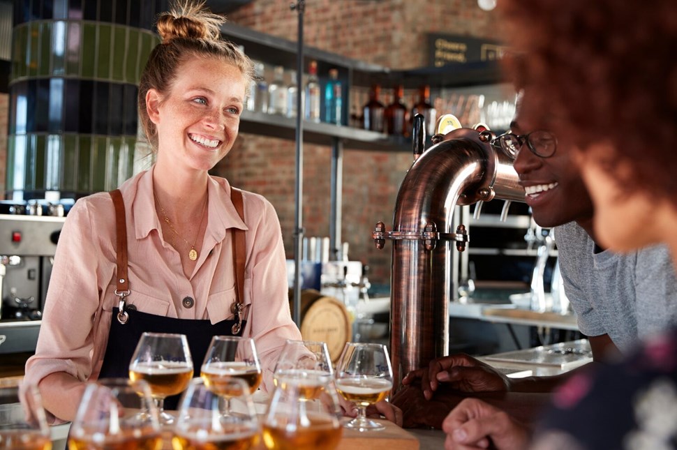  Waitress Serving Group Of Friends Beer Tasting In Bar