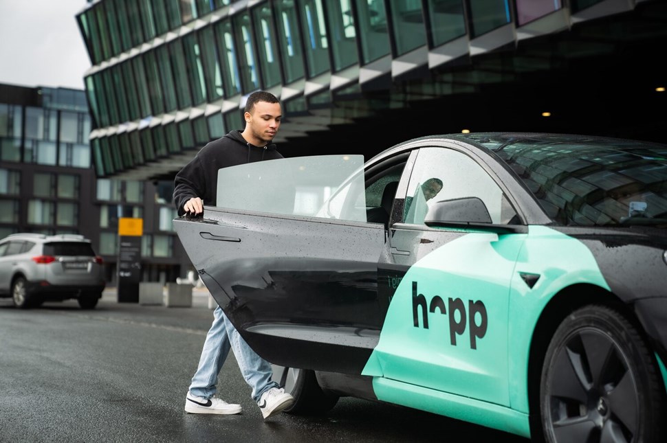 Man opens the door to a Hopp ride service car outside Keflavik Airport.