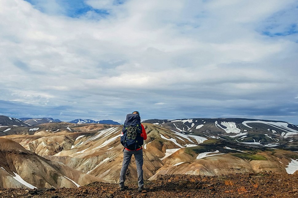 Hiker with backpack standing over the mountains of Landmannalaugar.