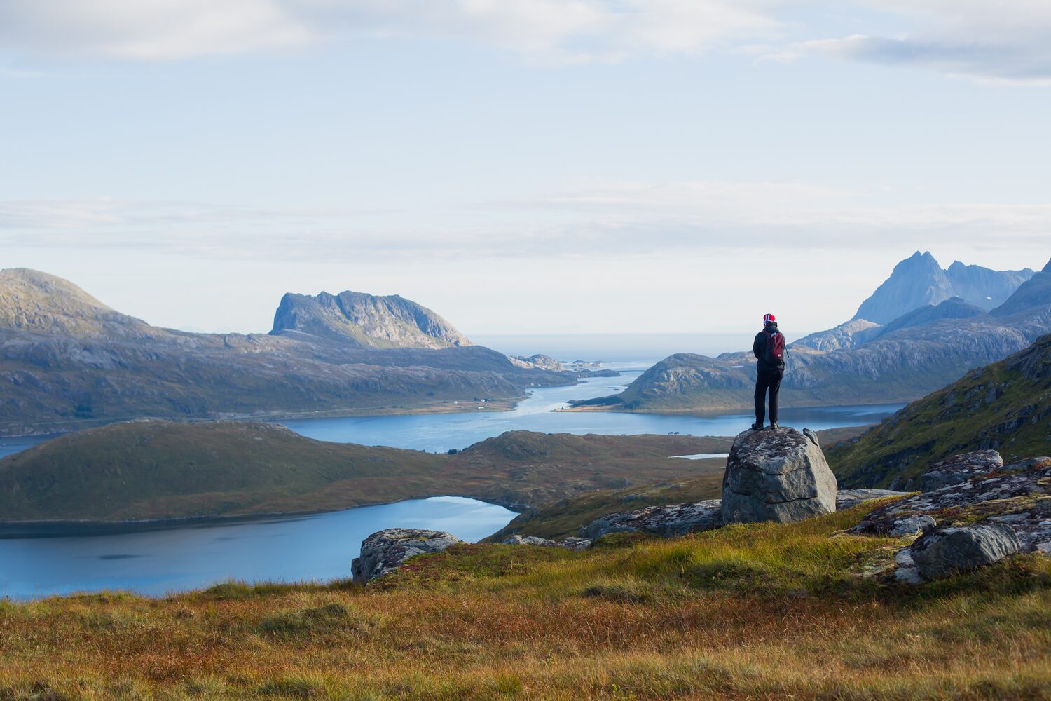 Person standing on the rock, looking over the mountains