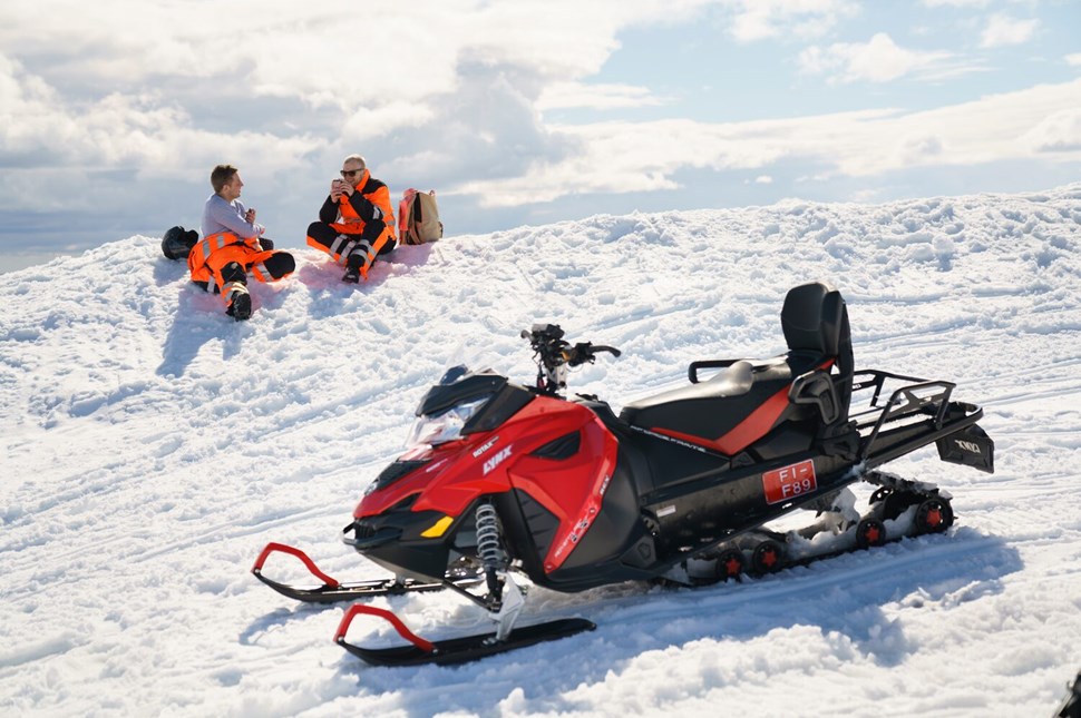 People getting rest on a glacier after snowmobiling