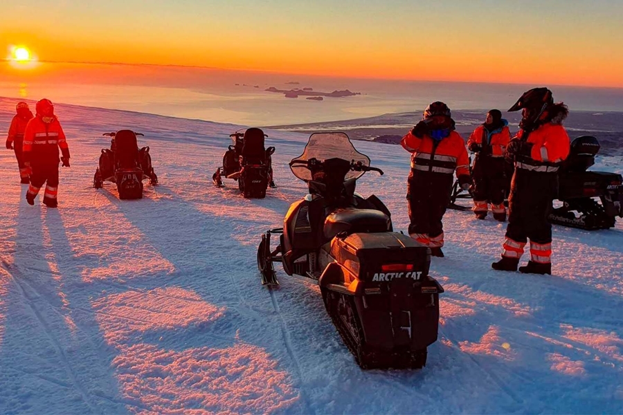 Snowmobilers on glacier by the sunset