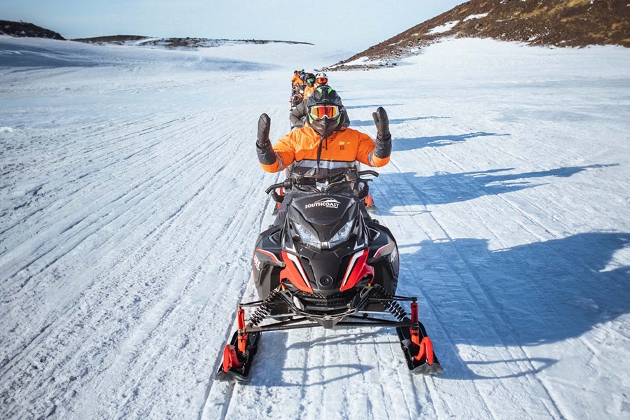People snowmobiling in a row