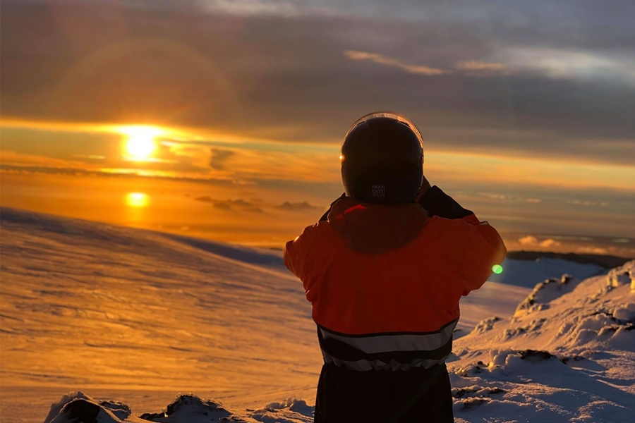 Snowmobiler watching sunset on a glacier