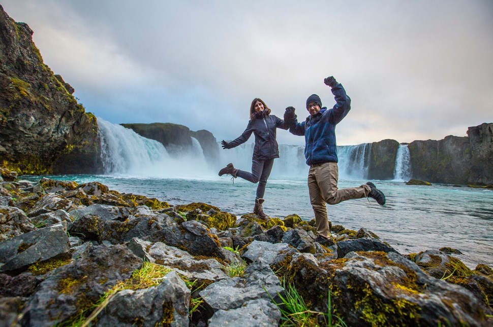 Posing couple holding hands near Godafoss waterfall 