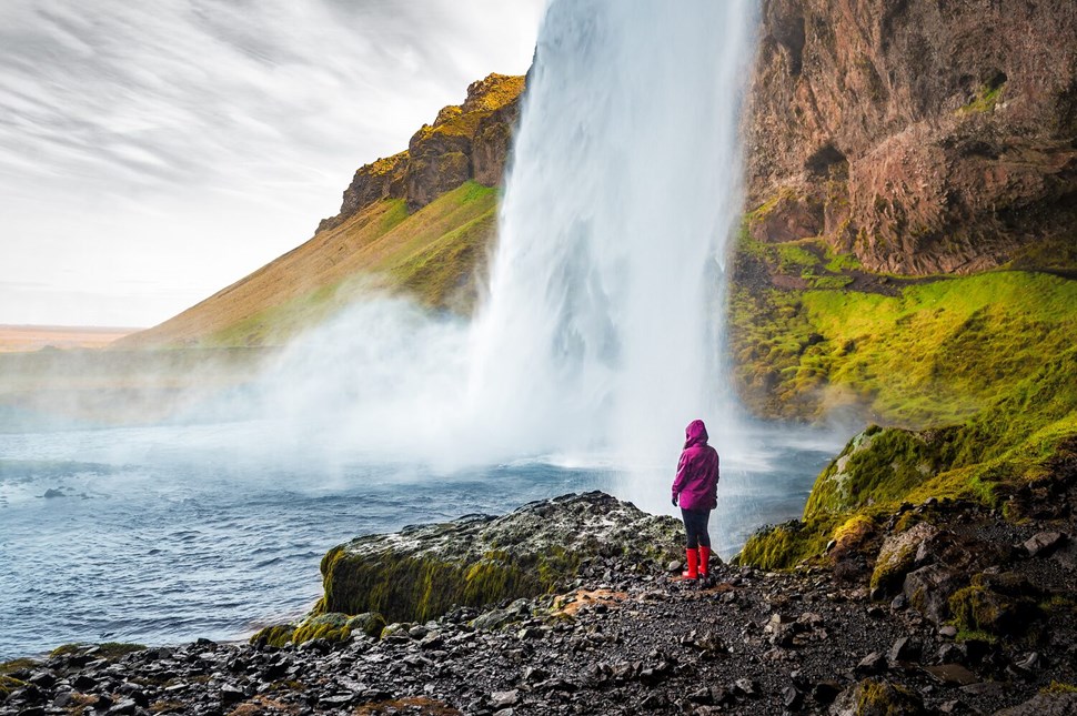 Woman standing by waterfall in Iceland