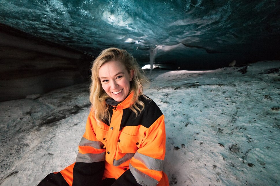 Woman in snowmobile costume inside an ice cave