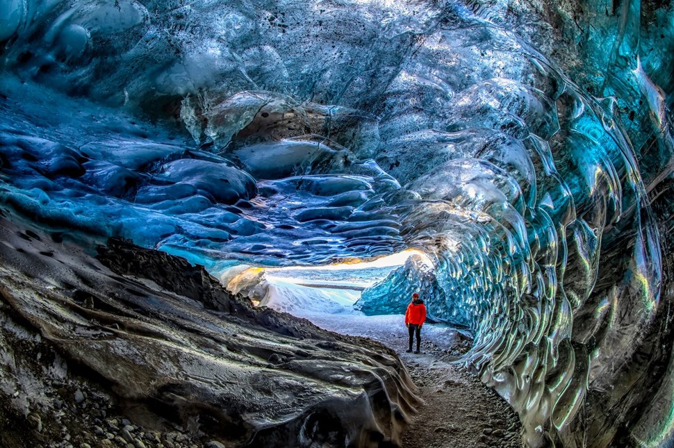 Man standing in beautiful blue ice cave