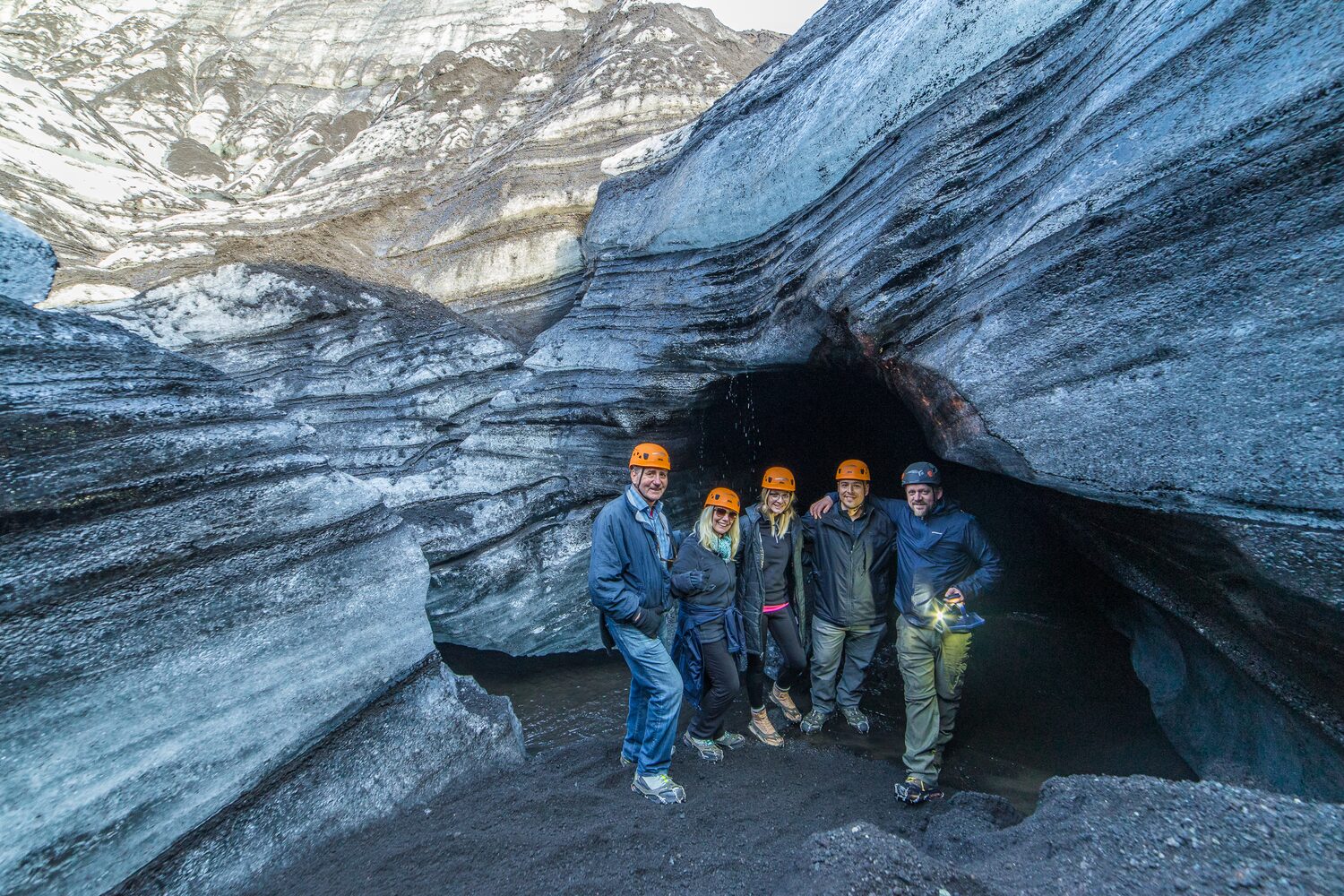 Group of people with helmets by ice cave