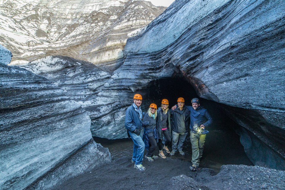 Group of people with helmets by ice cave