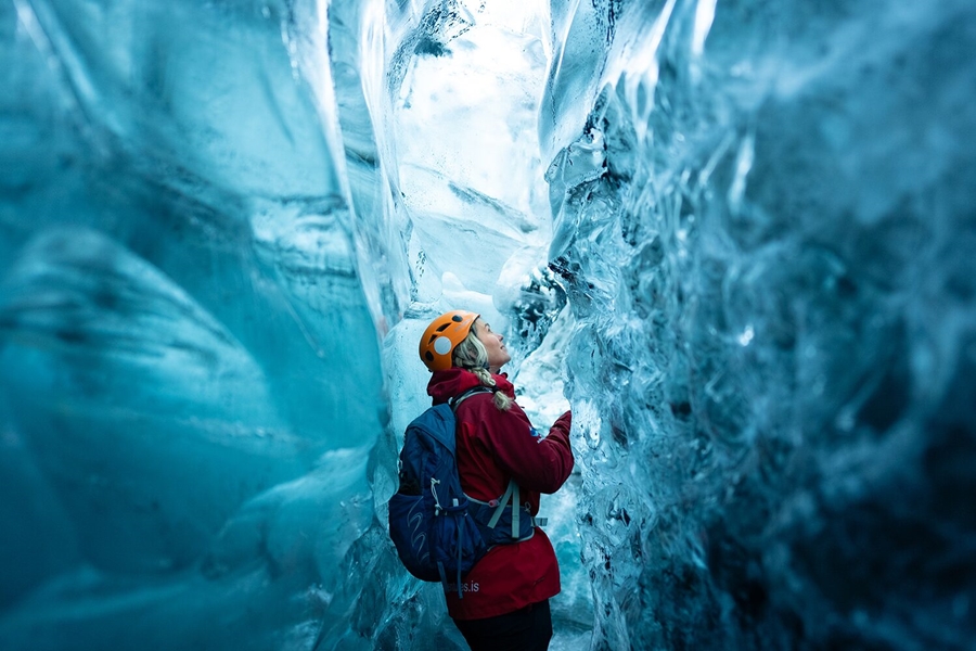 Woman inside ice cave wearing red jacket