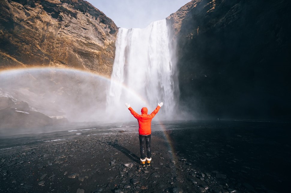 Woman with red jacket by waterfall in Iceland