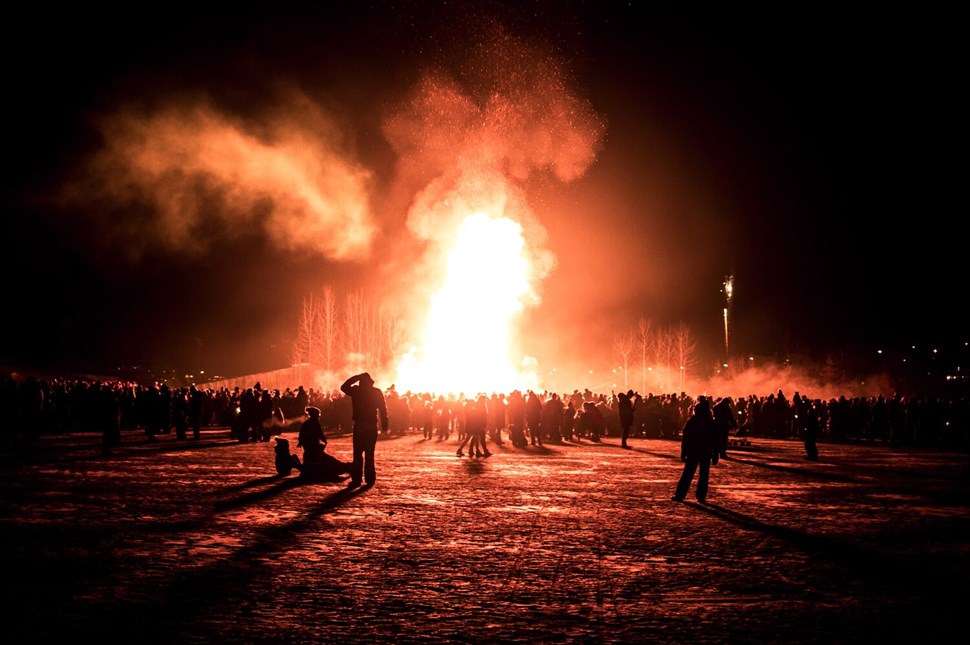 Large nighttime bonfire with people around
