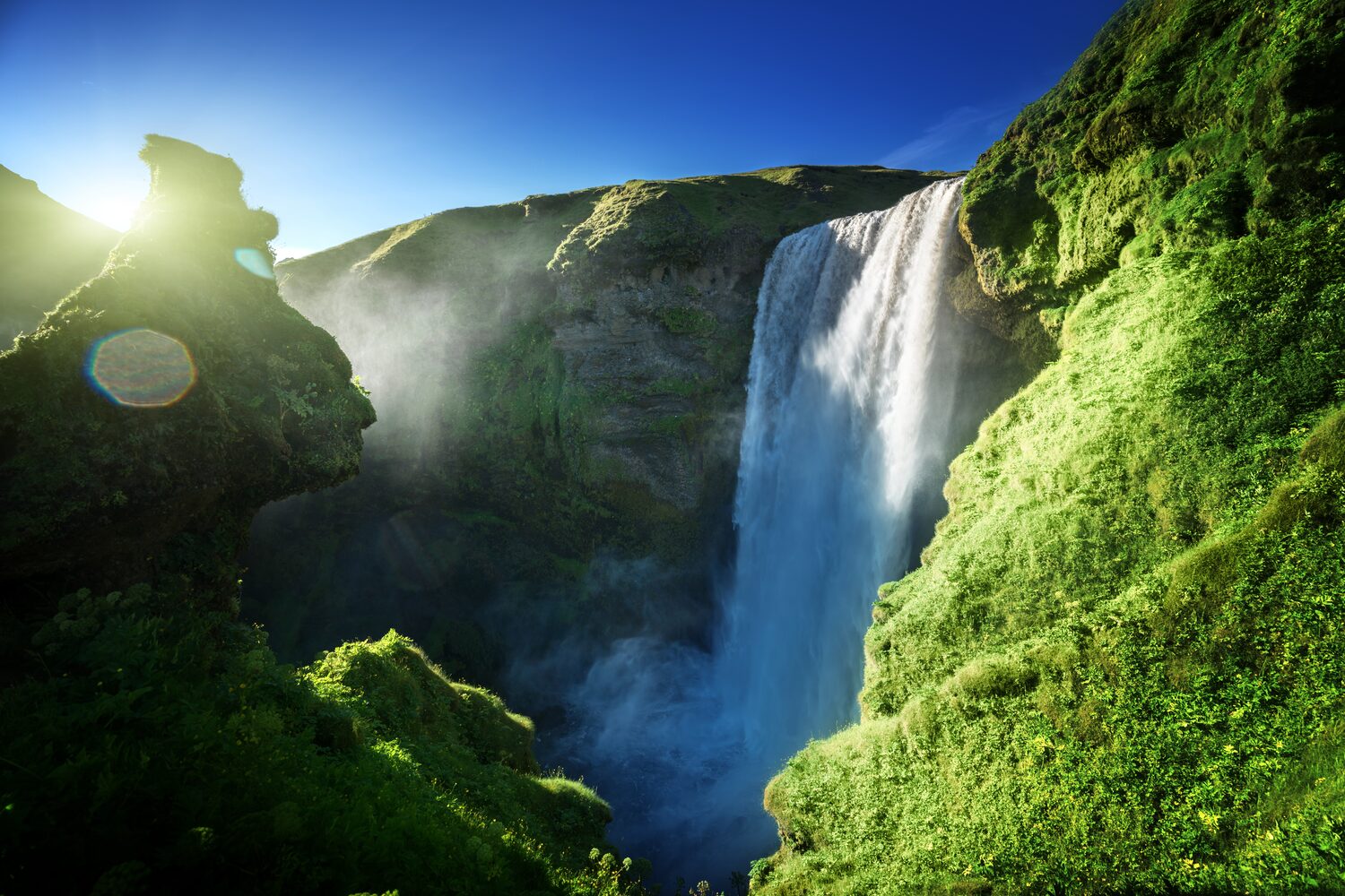Skogafoss waterfall and lush greenery on sunny day