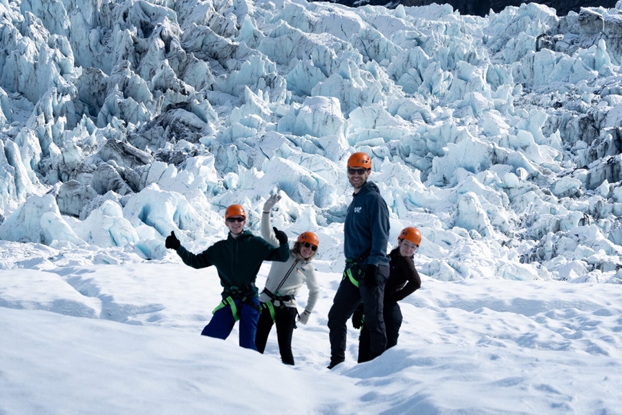 Four people posing for photo on glacier