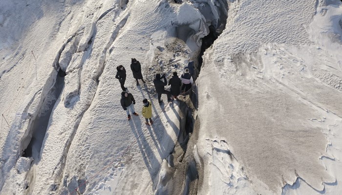 People walking near ice cracks on glacier