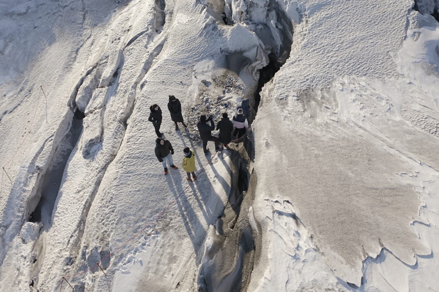 People walking near ice cracks on glacier