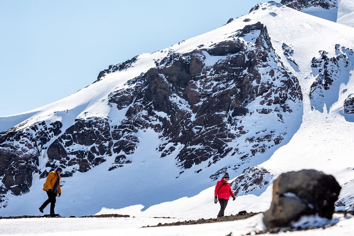 People walking by mountains on glacier