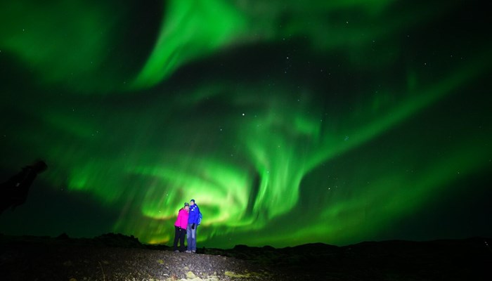 Couple posing for photo with Northern lights above