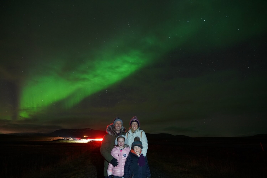 Family with two children posing for photo with Aurora
