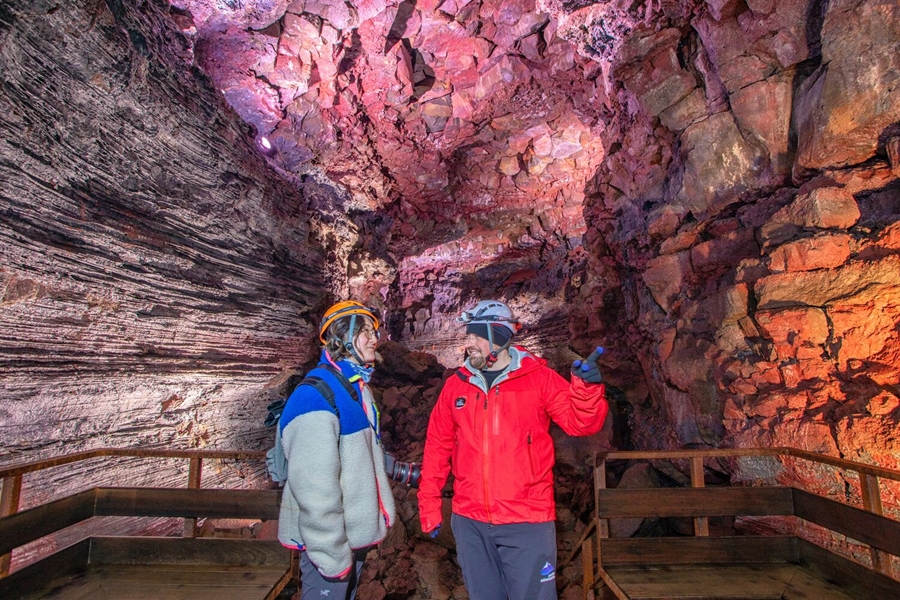 Woman and man exploring pink lava tube in Iceland