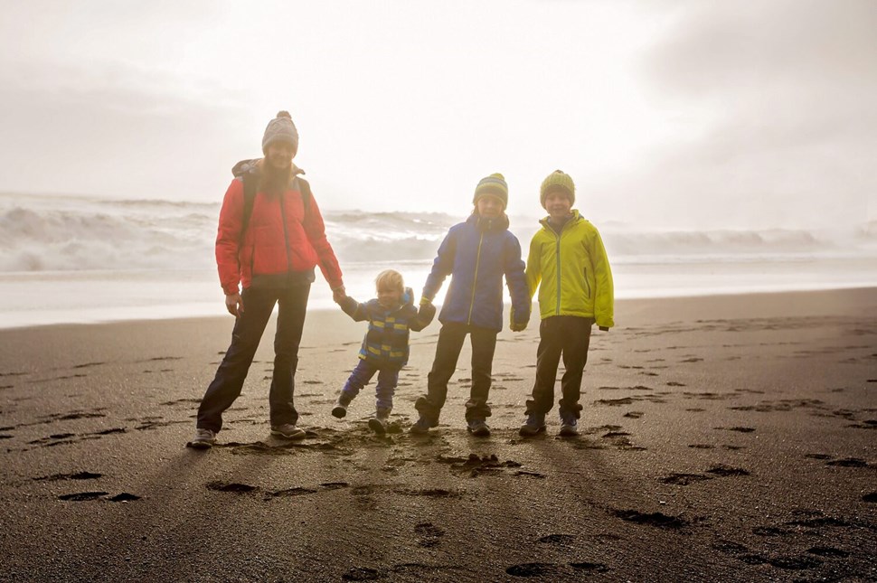 Mother with three children in Icelandic black sand beach