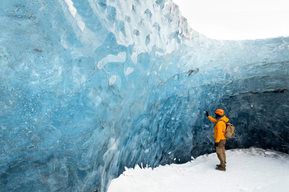 Man touching blue ice cave wall