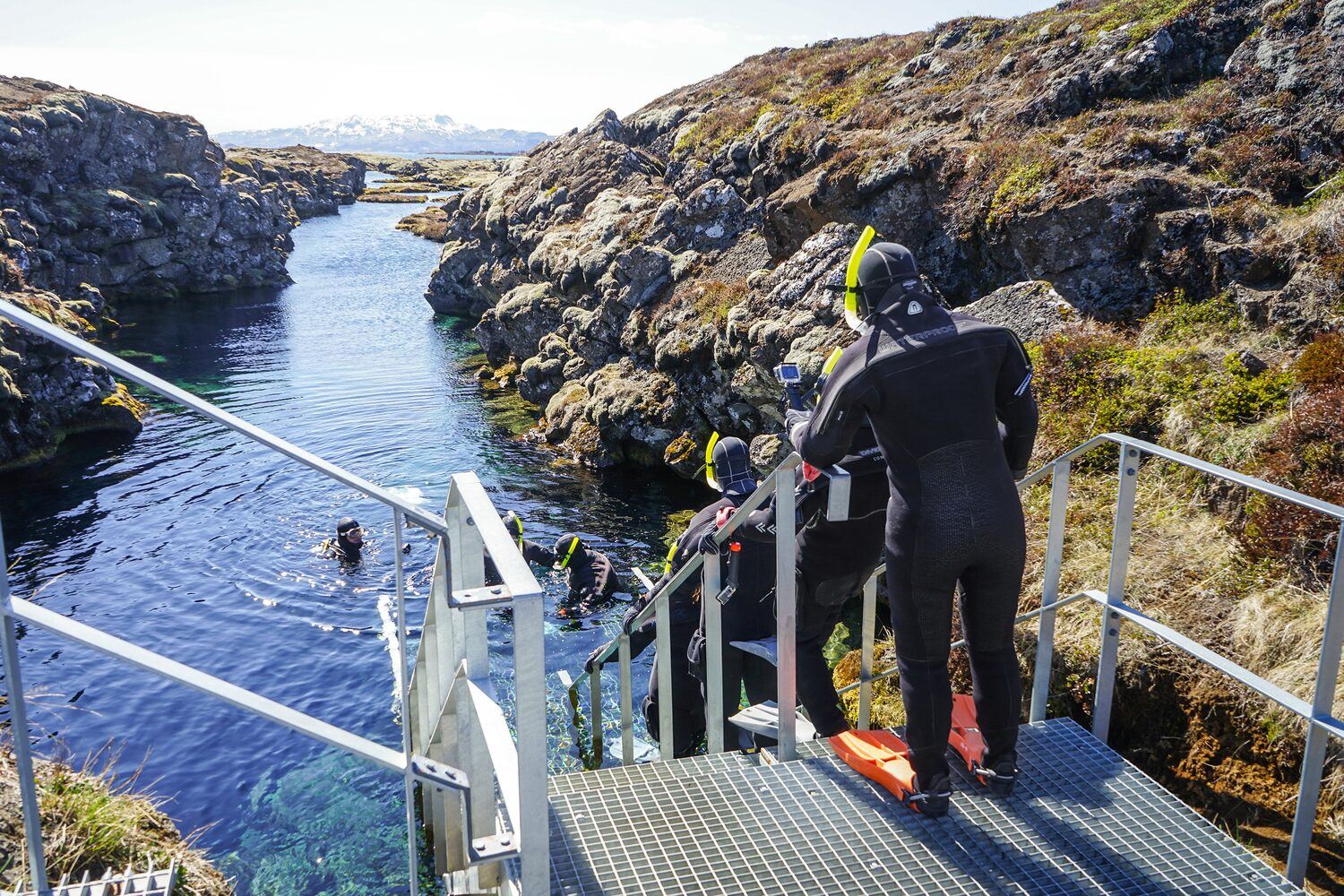 Group of people walking down stairs in Snorkeling gear into Silfra Rift waters 