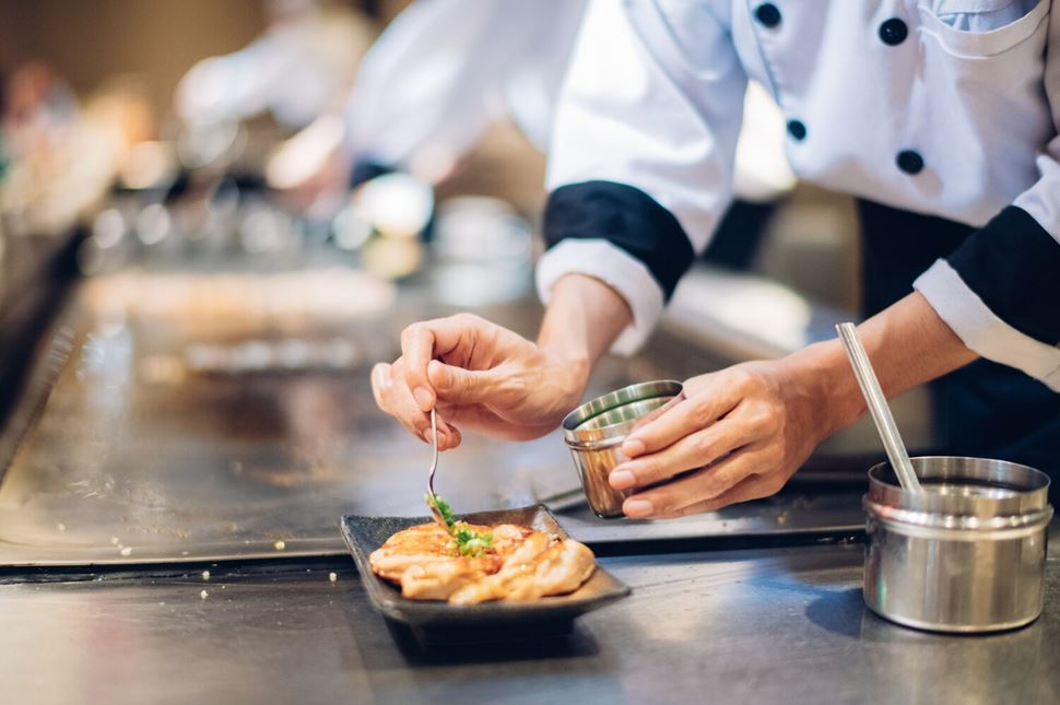 Chef Matey festival Mans hands adding garnish to meat with vegetable grill, Chef cooking wagyu beef in Japanese teppanyaki restaurant