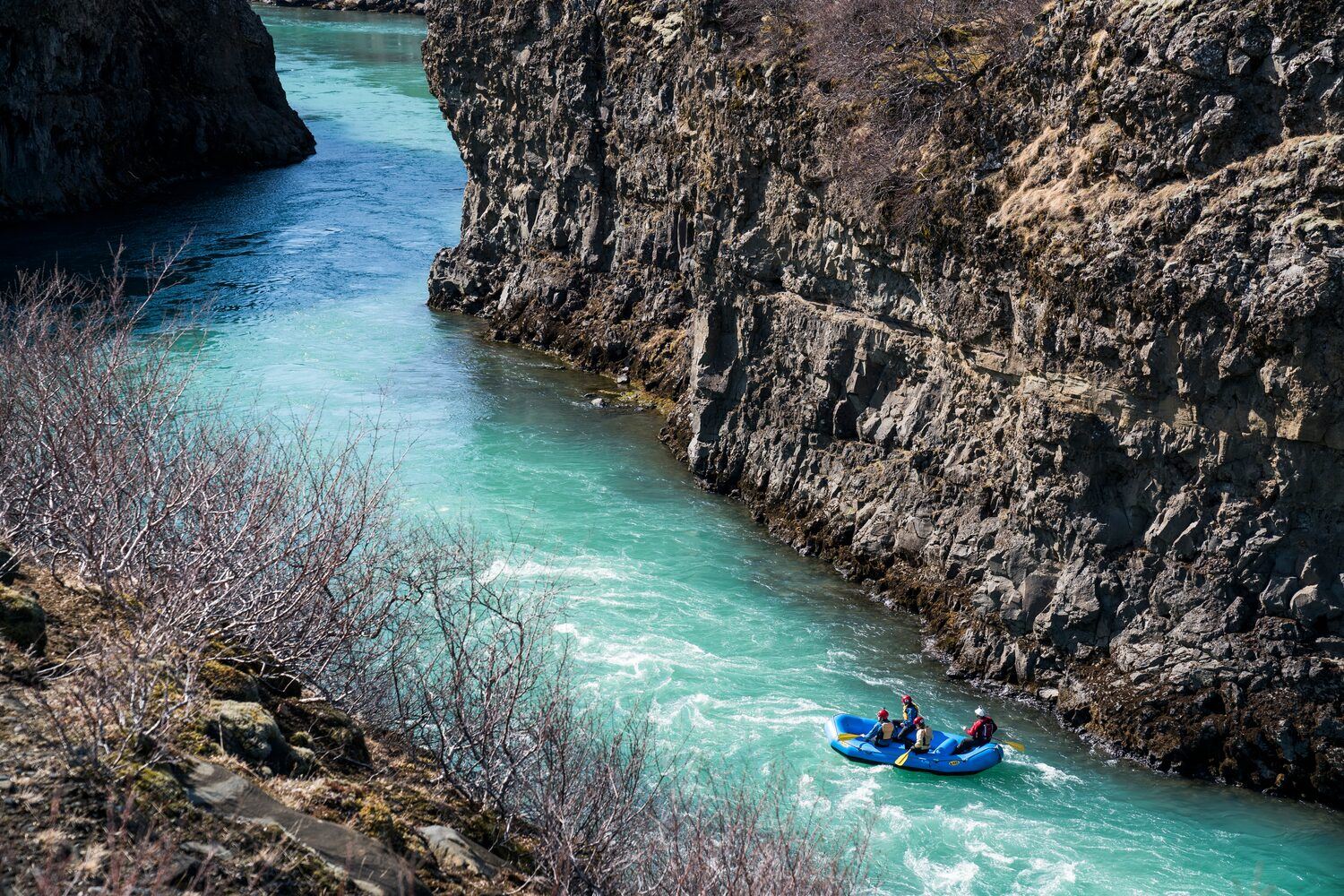 Four people in a blue raft, flowing down the Gullfoss Canyon, in Hvítá river, southwest Iceland